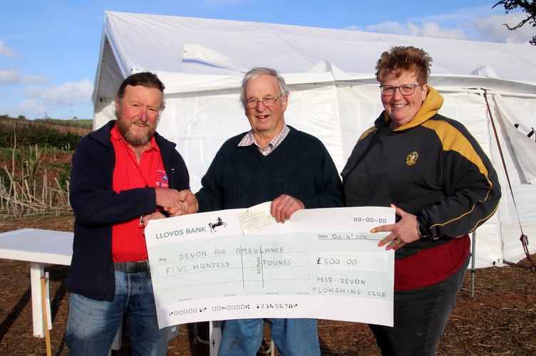 John Groves, left, receiving the cheque for Devon Air Ambulance from Mid Devon Ploughing Club chairman Eddie Vigers and match secretary Fiona Mortimer.  AQ 9182
