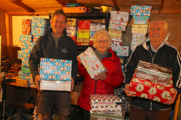 Margaret Tucker and her partner Derek Shapland and Biffo Holland, pictured with some of the 107 filled shoeboxes which left her home in November.  AQ 9271
