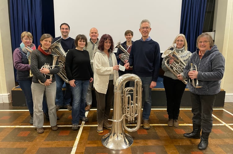 Crediton Town Band chairman James Hatchell presenting the cheque to Jane Williams of The Turning Tides Project, pictured with other Town Band members.  AQ 2086
