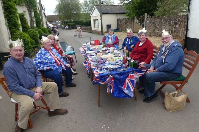 Some of the tables of people enjoying the shared lunch in the street at Cheriton Fitzpaine to mark the King’s Coronation.  