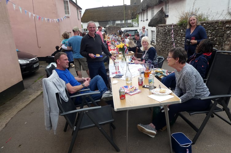 Some of the tables of people enjoying the shared lunch in the street at Cheriton Fitzpaine to mark the King’s Coronation.  