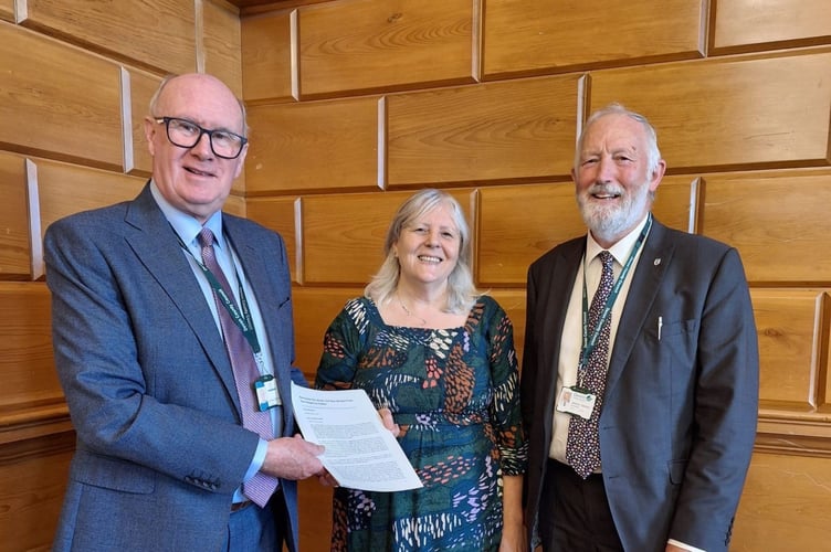 Cath Cottingham and Cllr Jeremy Yabsley, right, present the bus petition to Cllr James McInnes at County Hall