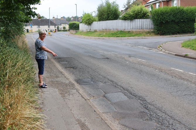 Carol Fletcher with open and patched potholes on Exhibition Road, Crediton