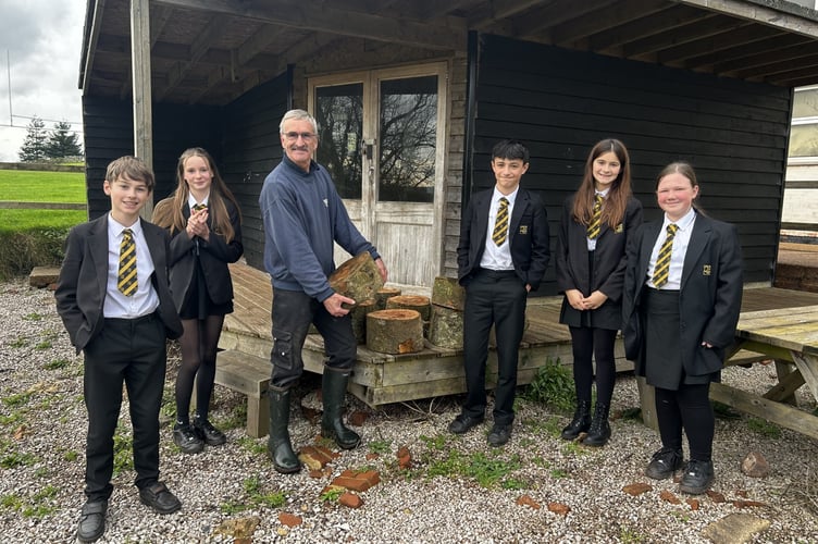 Roger Pennington delivering tree-stumps for the log seats, pictured with some QE students.
