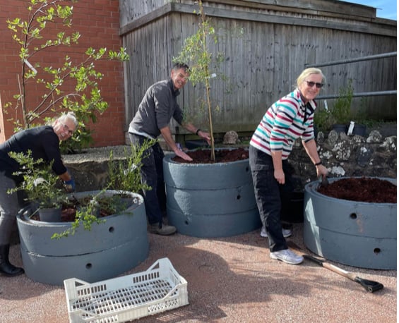 Members of Bow and District Garden Club help to plant up the new planters outside the village hall